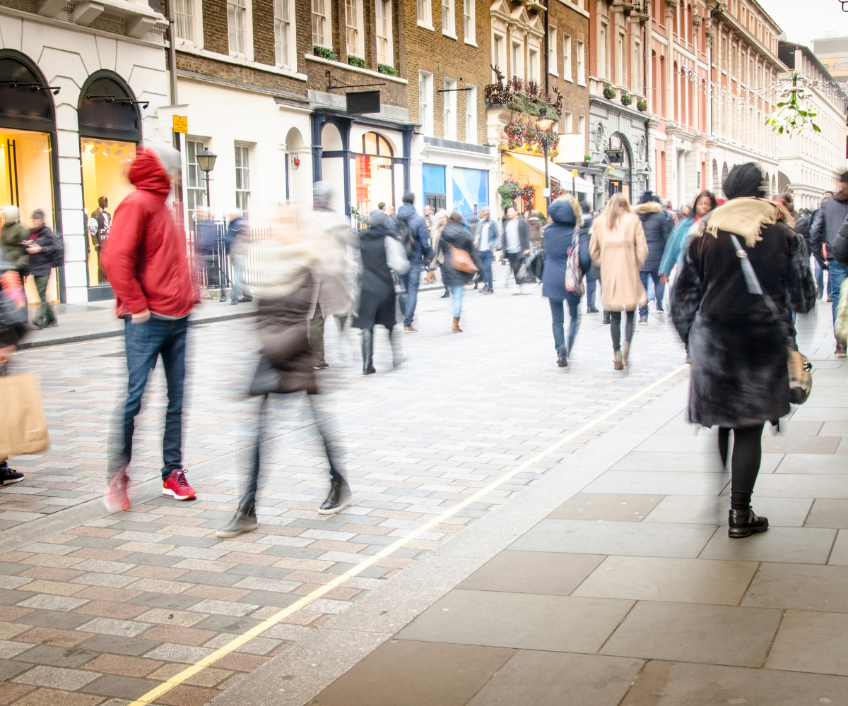 A wide, car-free street with lots of people walking up and down it.