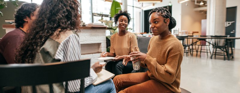 A group of young people talking and smiling as they sit facing each other.
