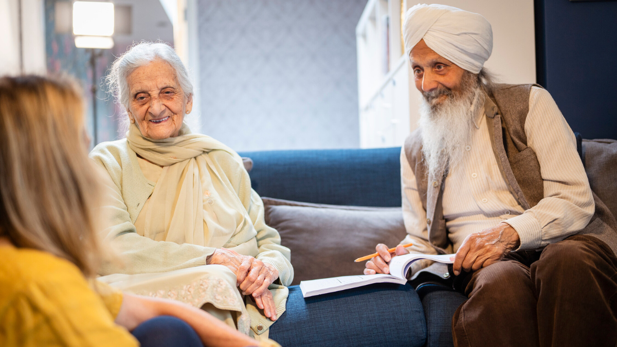 A photo of three people sitting in a living room, two of them are sat opposite the camera