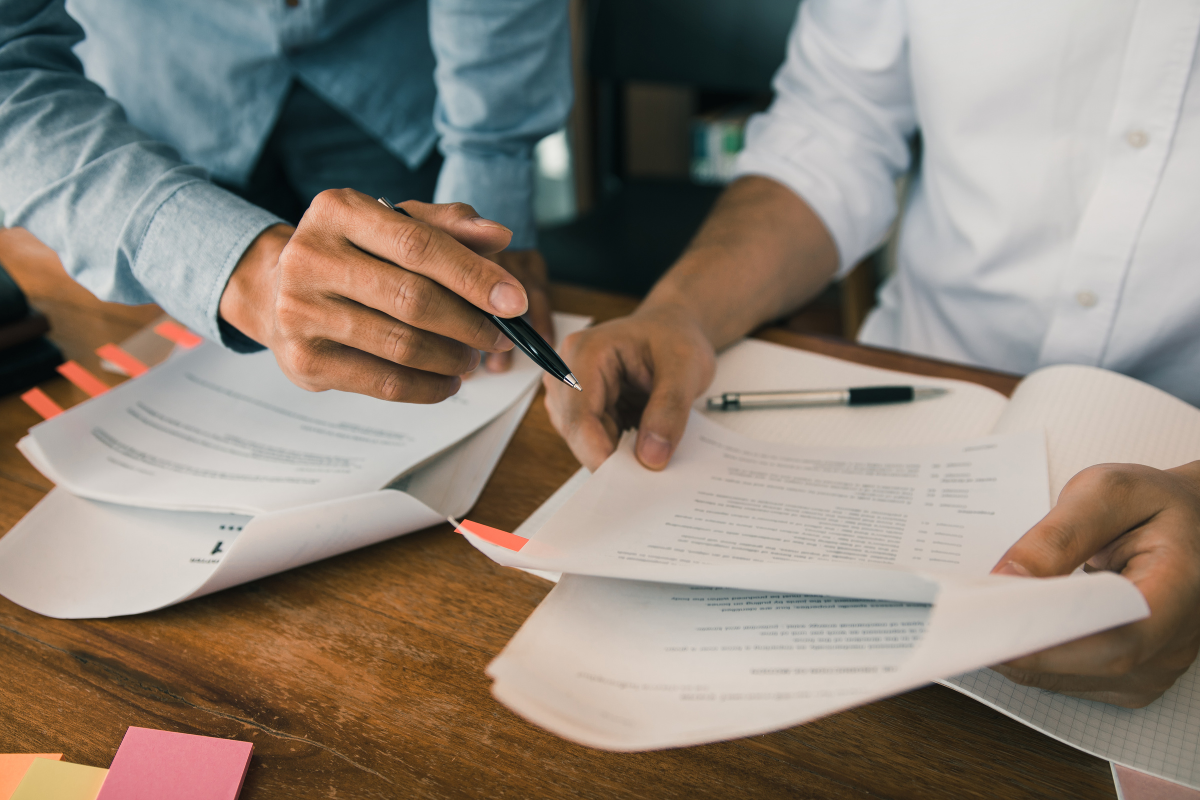 A photo of two people holding paperwork in their hands and making notes