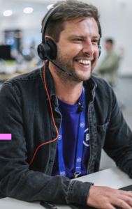 A photo of a BT volunteer sat at a computer with a headset on. They are smiling.